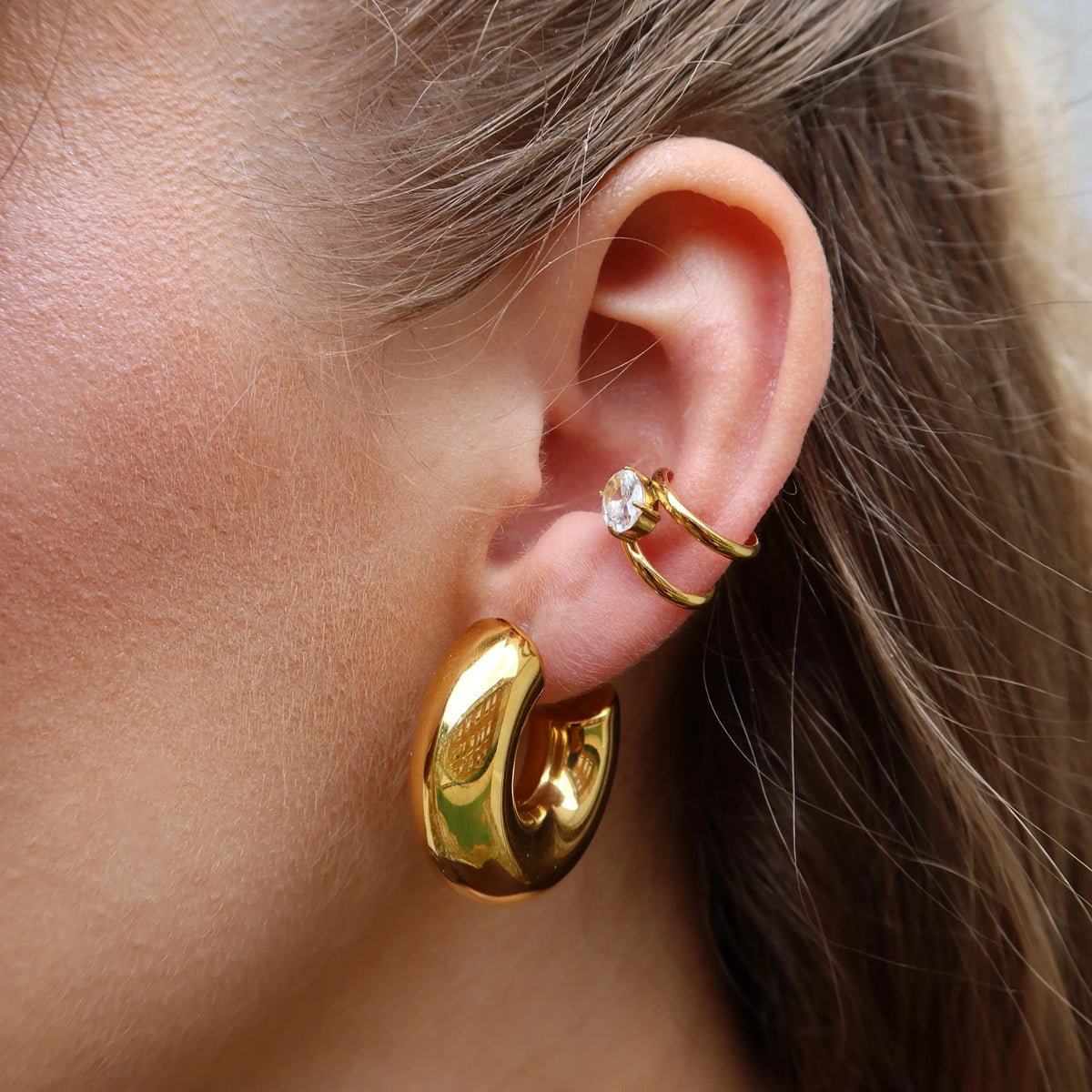 Delia Ear Cuff in Gold mit Zirkonia-Stein und Ava Hoops Ohrclips am Ohr getragen